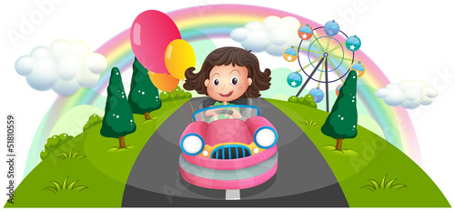 A young girl riding in a pink car with balloons
