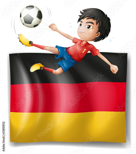 A boy playing soccer in front of the flag of Germany