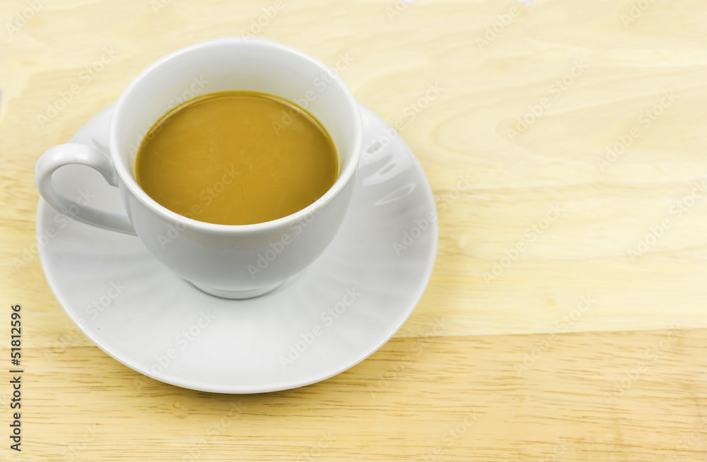 A cup of coffee with creamer on chopping board A cup of coffee with creamer on chopping board