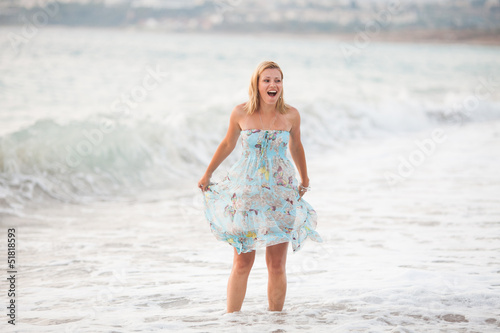 Young beautiful woman standing on beach near waves