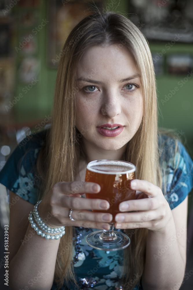 Blonde Woman with Beautiful Blue Eyes Drinks a Goblet of Beer Blonde Woman with Beautiful Blue Eyes Drinks a Goblet of Beer