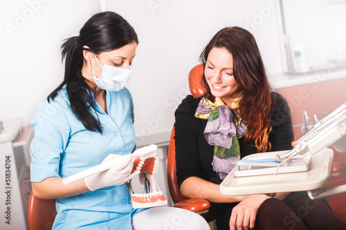 Dentist explains tooth care on a teeth model to patient. 