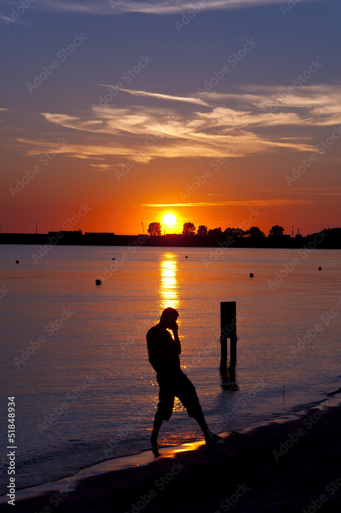 Silhouette of man talking by his mobile during sunset