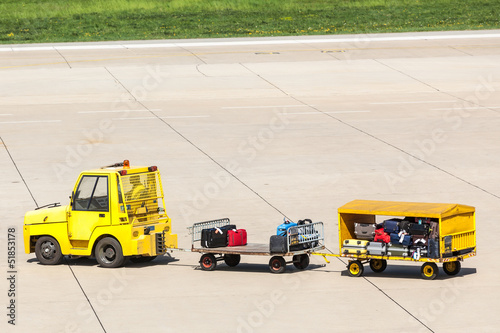 Yellow Freight trolleys with loaded baggage on the runway tarmac