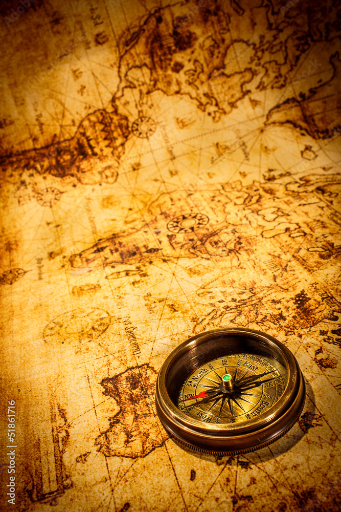 Obraz premium Vintage kompas leży na starożytnej mapie świata.