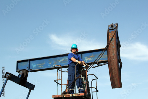 oil worker with sunglasses standing at pump jack