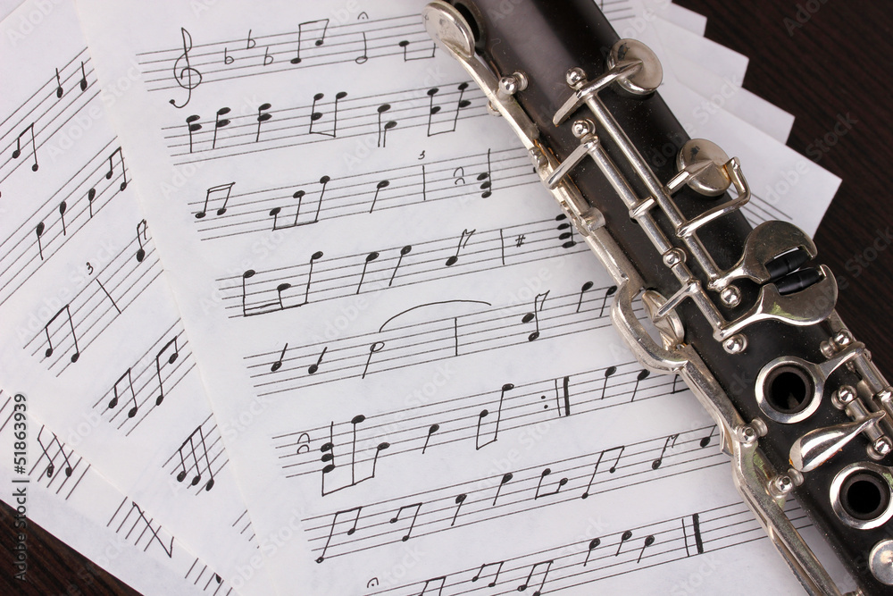 Obraz premium Musical notes and clarinet on wooden table