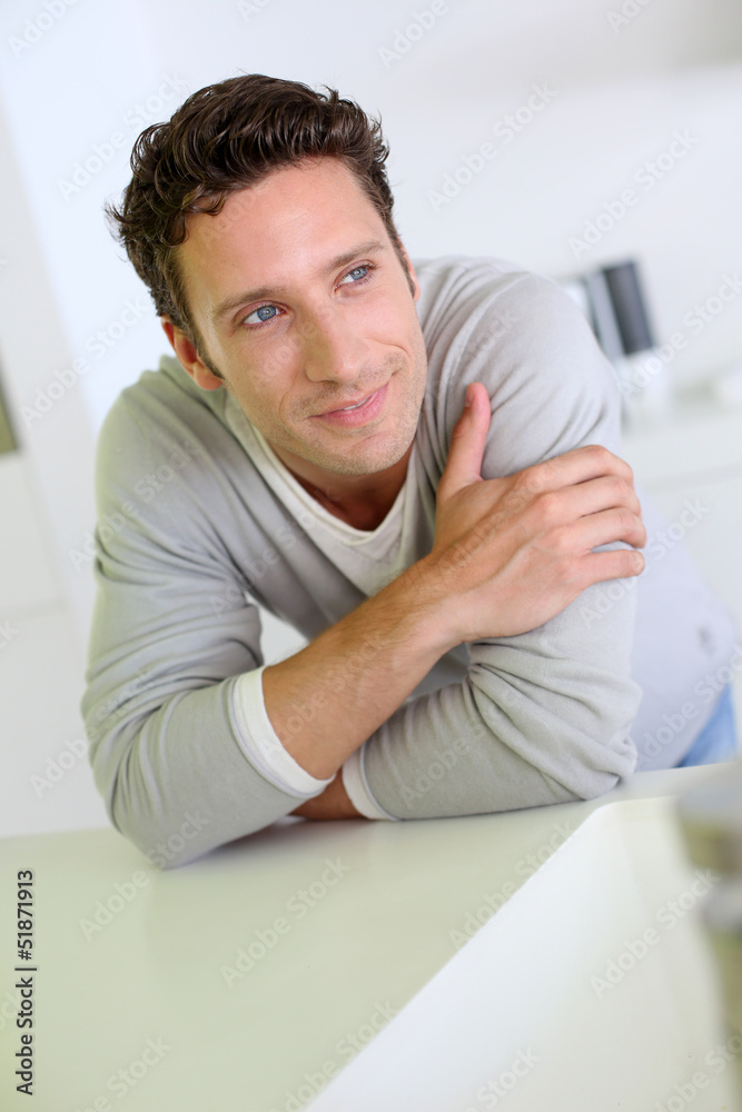 Portrait of handsome man leaning on kitchen counter