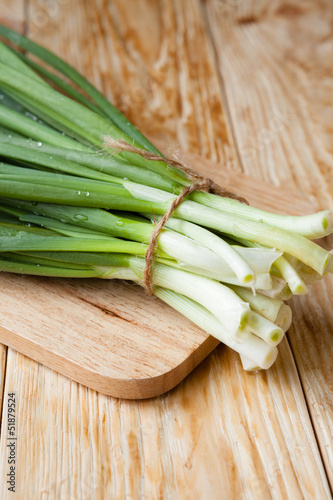 fresh green onions on a wooden surface