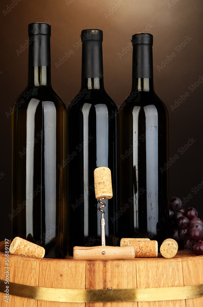 Naklejka premium Wine and corks on barrel on brown background