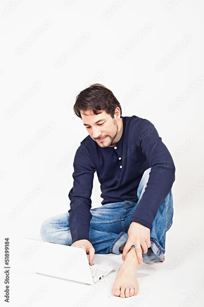 young man working on laptop while sitting on the floor young man working on laptop while sitting on the floor