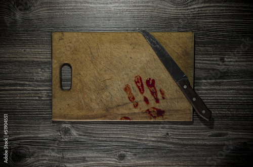 wooden background with a bloody hand print on the cutting board