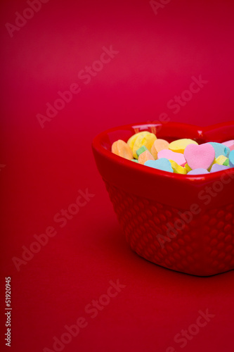 a candy dish is filled with heart candy on red