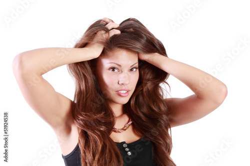 Young brunette woman touches her hair and looks at camera