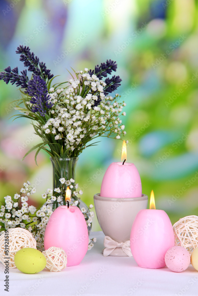 Easter candles with flowers on bright background