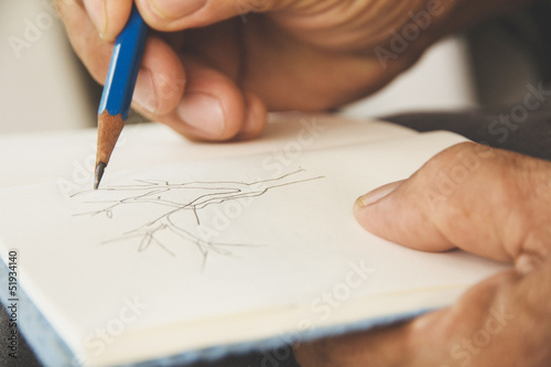 man writing on sketchbook