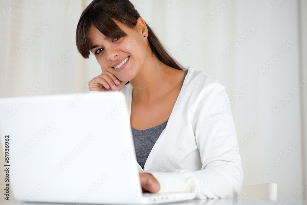 Smiling young woman looking at you using laptop Smiling young woman looking at you using laptop