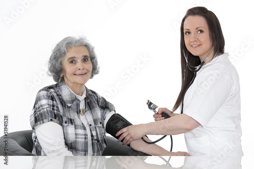 Junge Ärztin misst den Blutdruck einer alten Frau