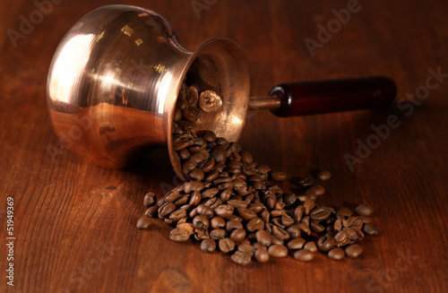 Coffee pot with coffee beans on brown wooden background