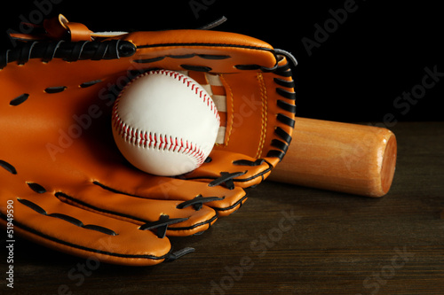 Baseball glove, bat and ball on dark background