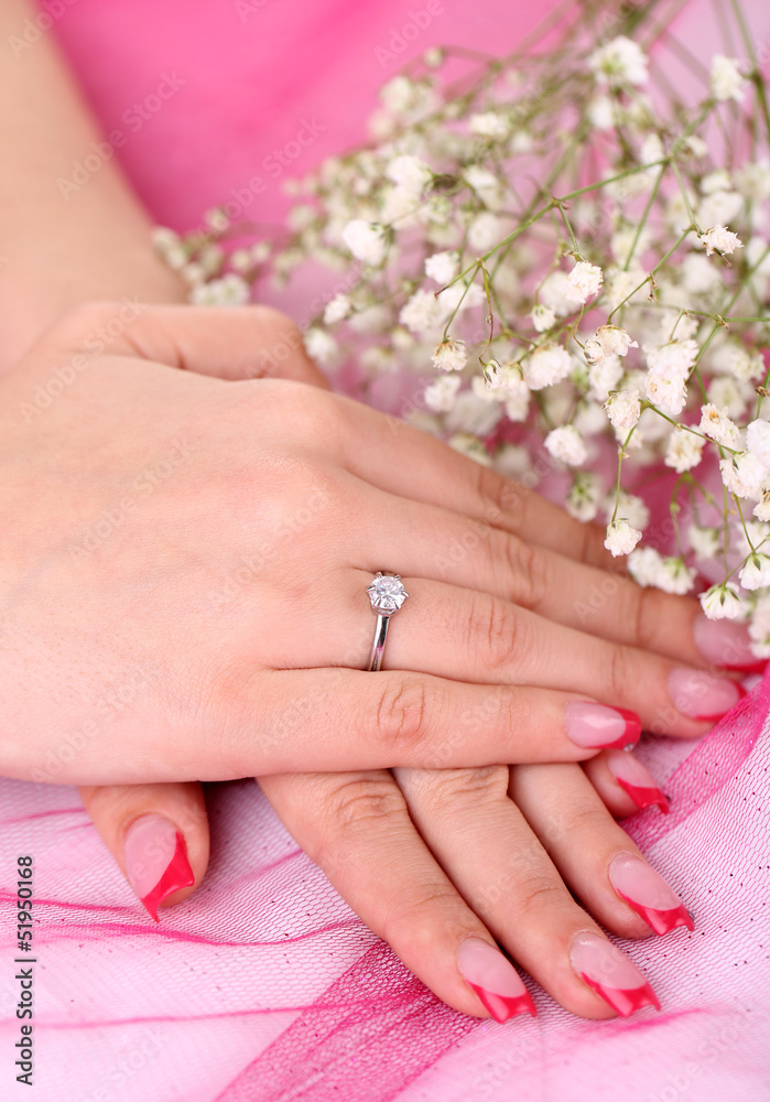 Hands and ring and flowers on a pink background Hands and ring and flowers on a pink background