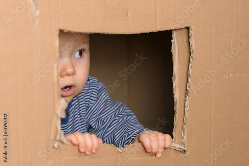 staunendes Baby schaut vorsichtig aus Fenster