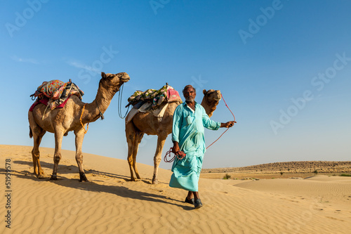 Cameleer  camel driver  with camels in dunes of Thar desert. Raj