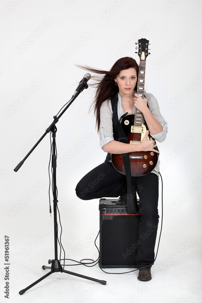 Fototapeta premium Musician hugging her guitar and posing with her equipment