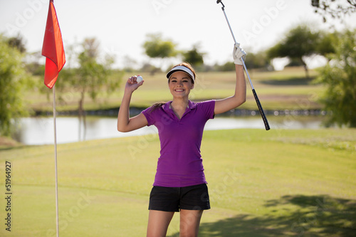 Happy female golfer celebrating her score and raising her arms