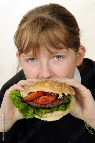 Schoolgirl eating a beefburger with a healthy salad filling