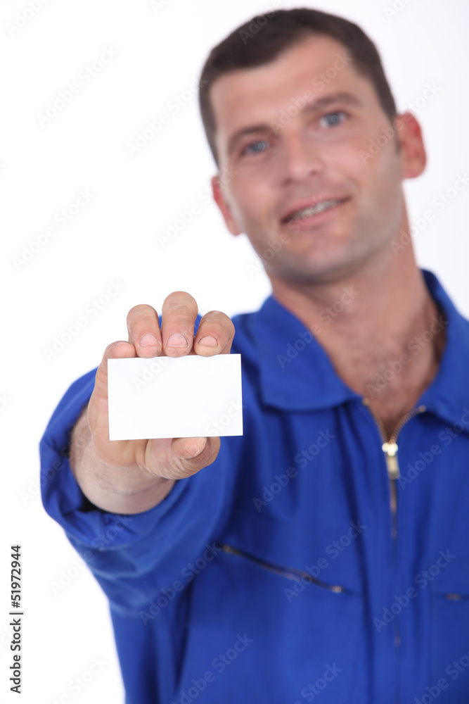 Man in blue overalls holding a business card left blank Man in blue overalls holding a business card left blank