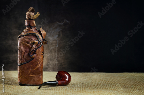 Leather vintage bottle with a pipe on a dark background
