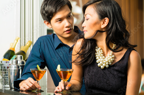 Man and woman in asia at bar with cocktails