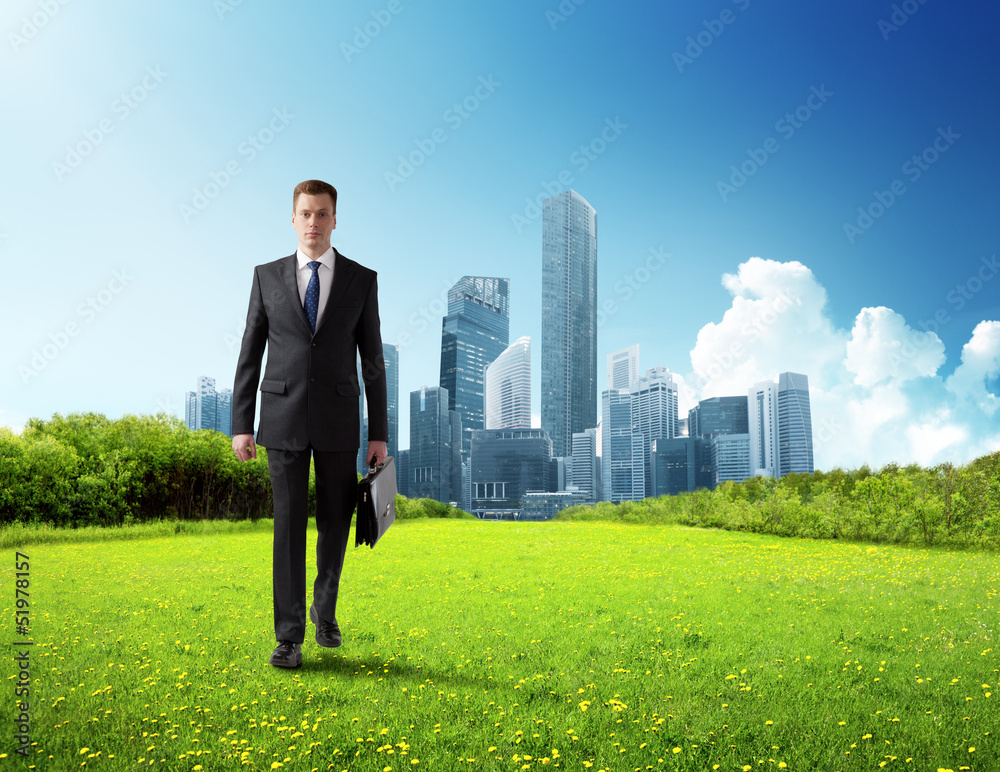 business man walking on green field and modern city business man walking on green field and modern city