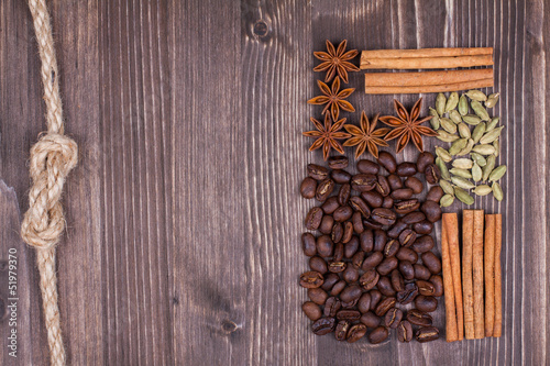 Coffee beans, cinnamon, star anise, cardamom on wood background