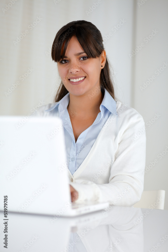 Young woman looking at you while working on laptop Young woman looking at you while working on laptop