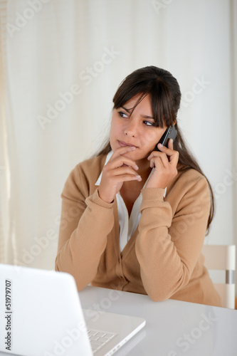 Pensive woman working and speaking on cellphone