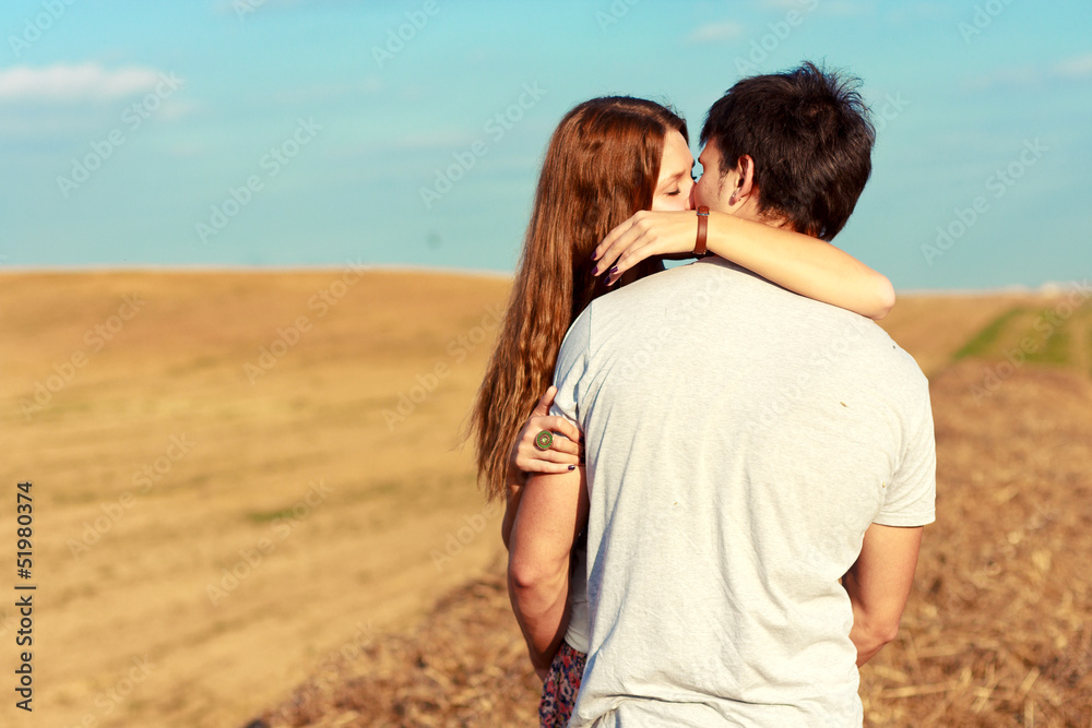 Young attractive couple in love kissing in summer in field Young attractive couple in love kissing in summer in field