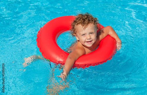 little boy in the swimming pool  with rubber ring © altanaka