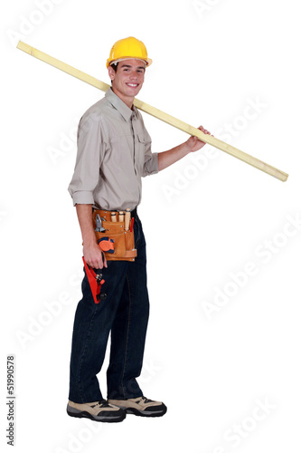young carpenter in studio carrying plank over his shoulder © auremar