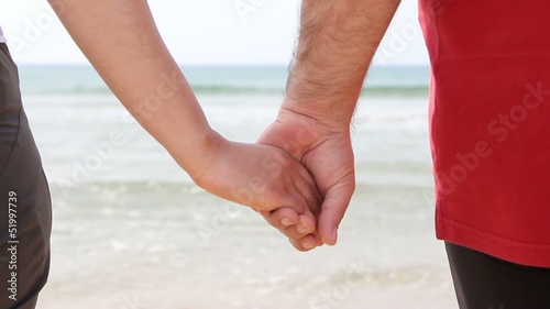 A young couple on the beach holding hands