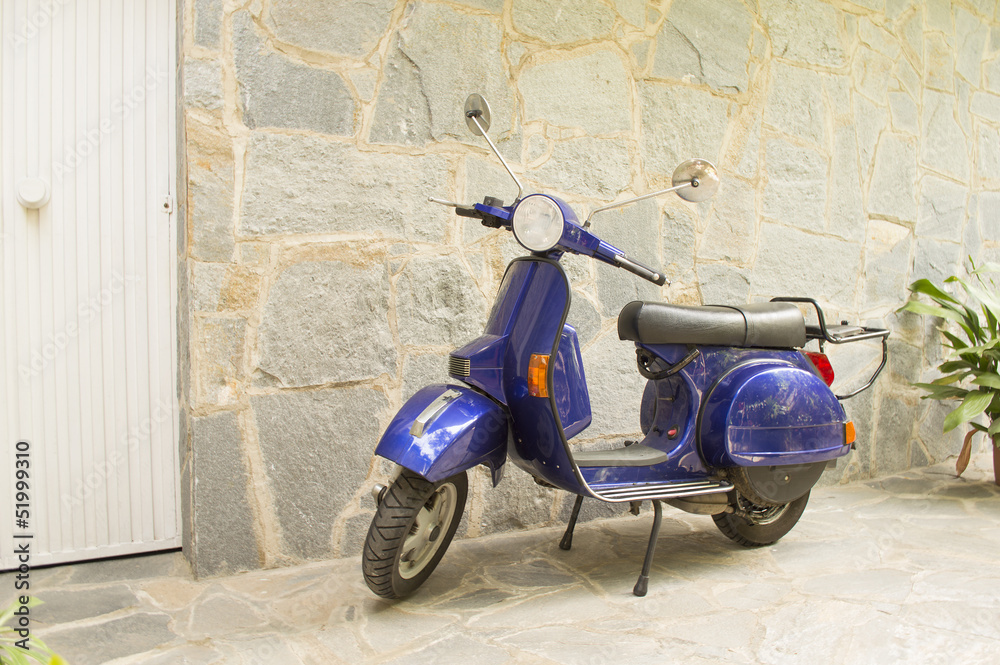 scooter parked in front of a stone house near the door