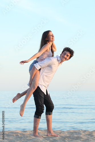 Couple playing piggyback on the beach