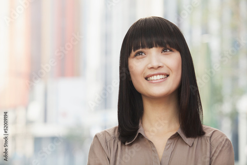 Portrait of smiling young woman outdoors in Beijing, looking up