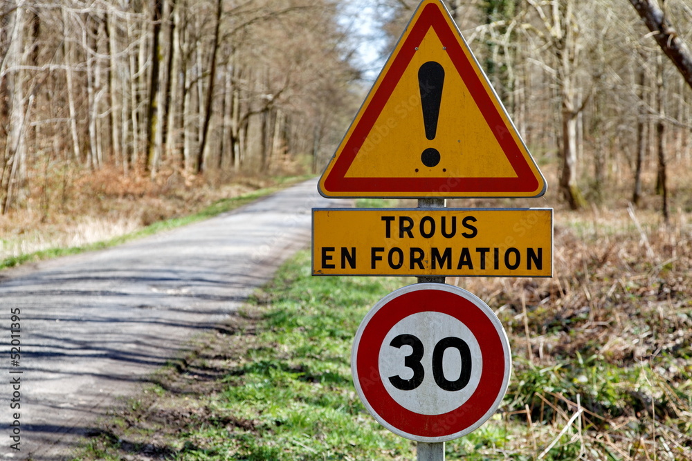 trous en formation, panneau sur route de forêt Photos Adobe Stock
