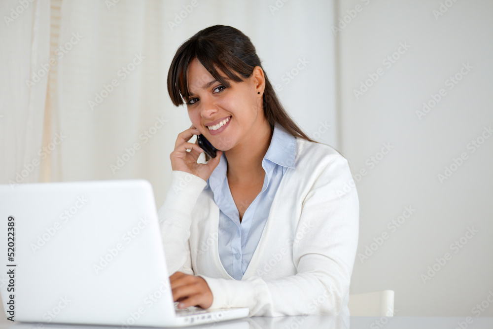 Smiling young woman looking at you using laptop Smiling young woman looking at you using laptop
