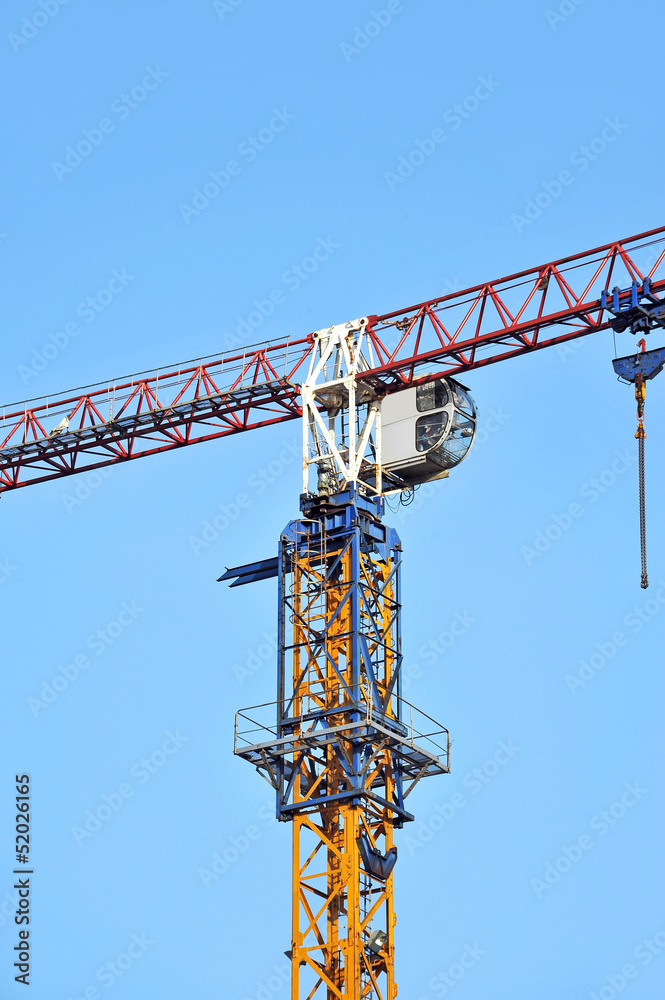 Tall construction tower crane against blue sky