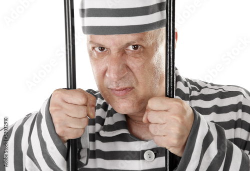 Фотография Angry convict prisoner jailbird behind bars