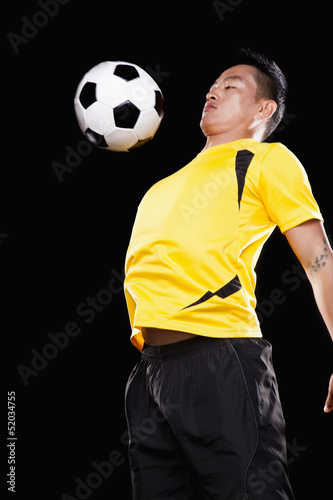 Footballer chesting ball  black background