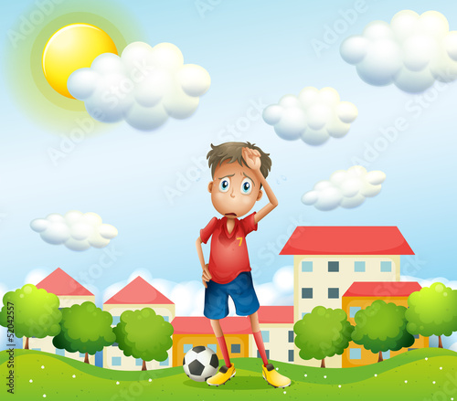 A tired boy standing with a soccer ball